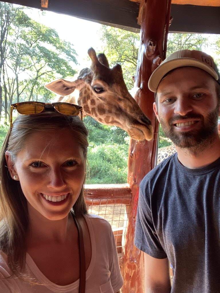 Travel couple taking a selfie with a resident giraffe at the Giraffe Centre in Nairobi
