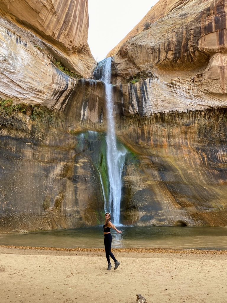 Sara twirling around in front of the waterfall at the end of the Lower Calf Creek Falls trail