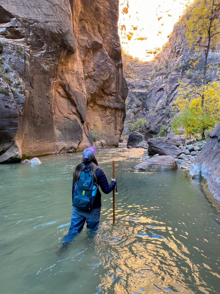 Sara with all of her gear hiking through the Virgin River at the Narrows in Zion National Park