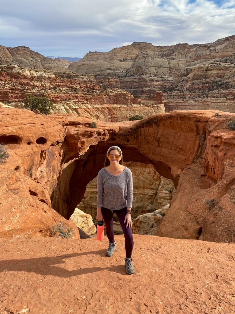 Sara standing in front of Cassidy Arch with her reusable water bottle at Capitol Reef