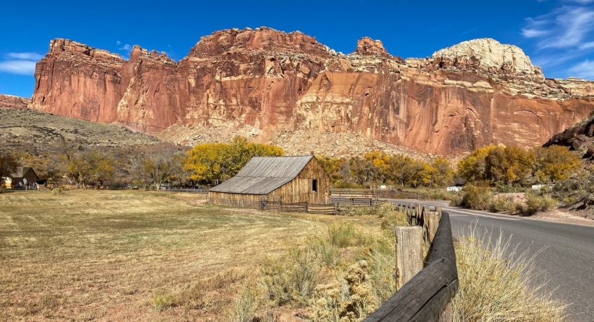 the Gifford Homestead with the colorful sandstone cliffs of the Waterpocket Fold in the background at Capitol Reef