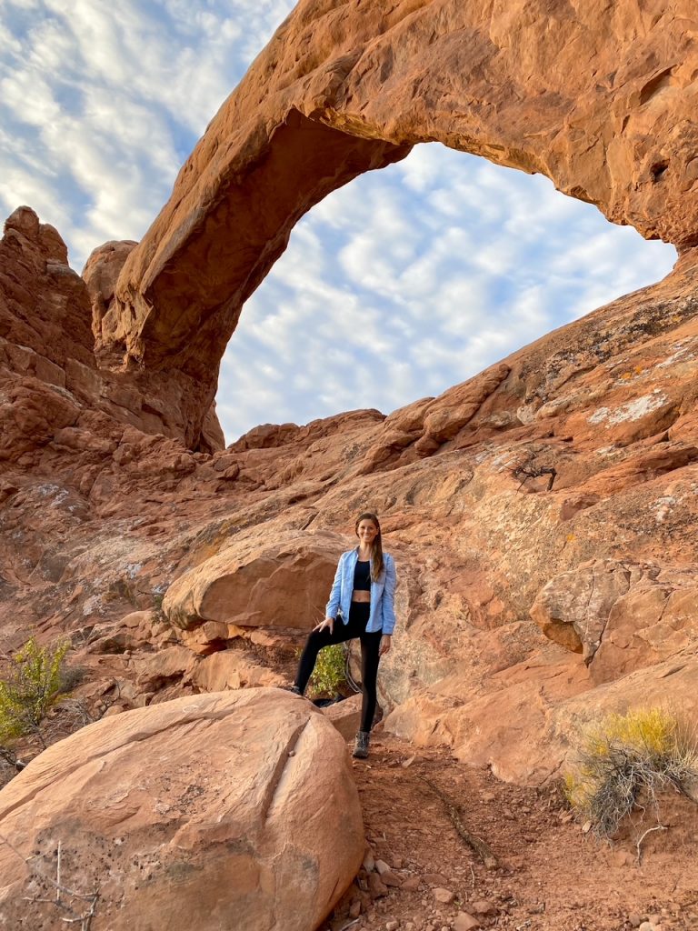 Sara in front of the North Window in The Windows area of Arches National Park, a popular stop on a Utah Mighty Five road trip