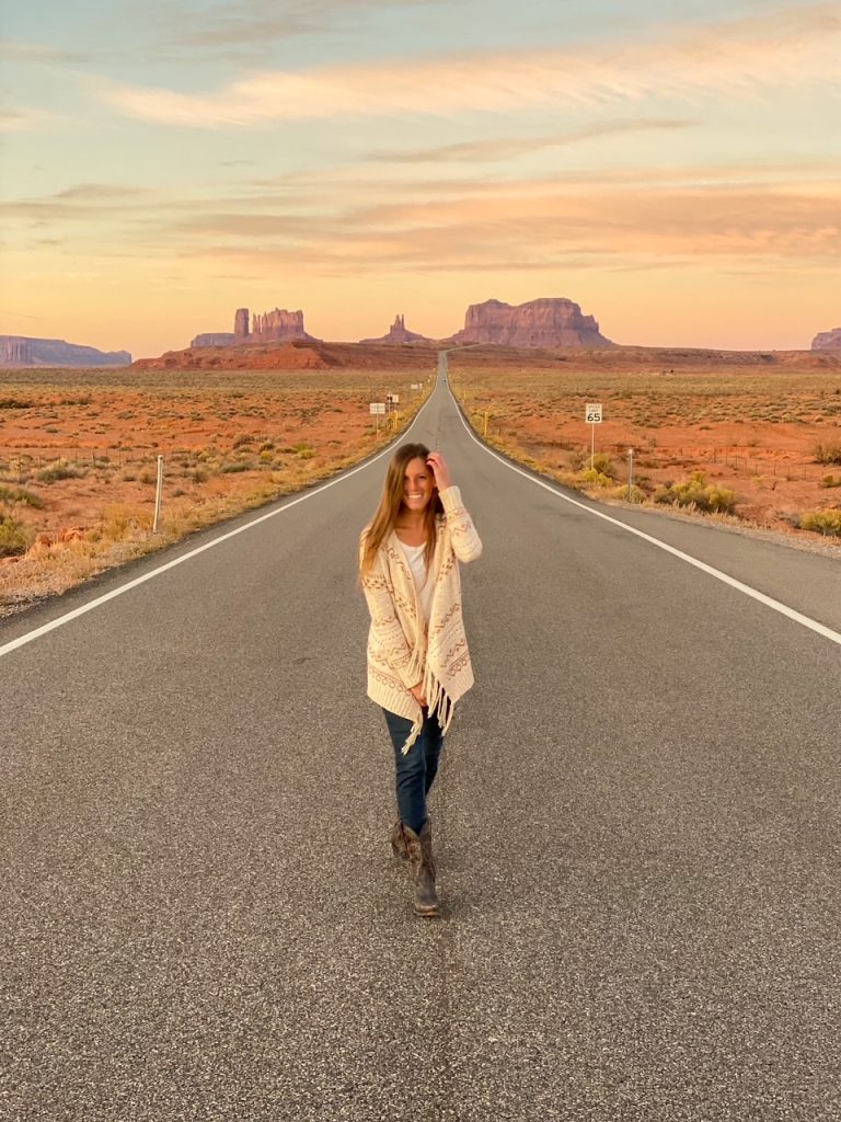 Sara posing at Forrest Gump Point on Highway 163, overlooking the sandstone buttes of Monument Valley near the Utah–Arizona border