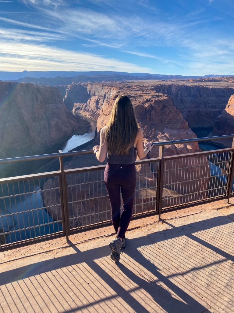 Sara standing at the railing overlooking Horseshoe Bend in Page AZ