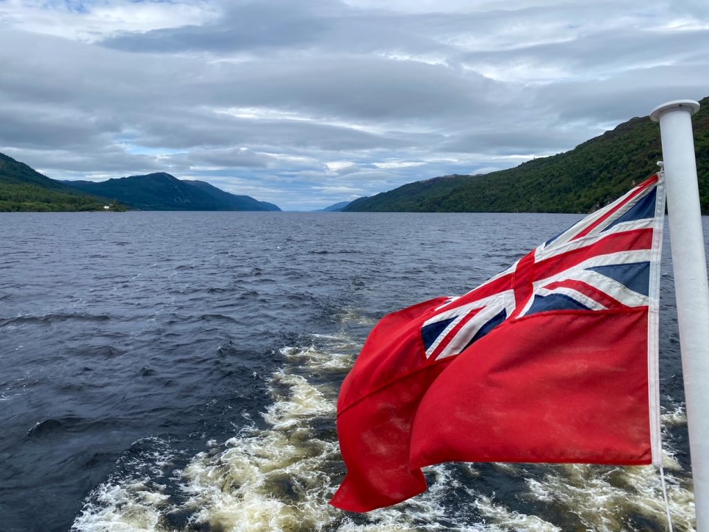 the Red Ensign, the flag flown by British merchant or passenger ships since 1707, with Loch Ness in the background