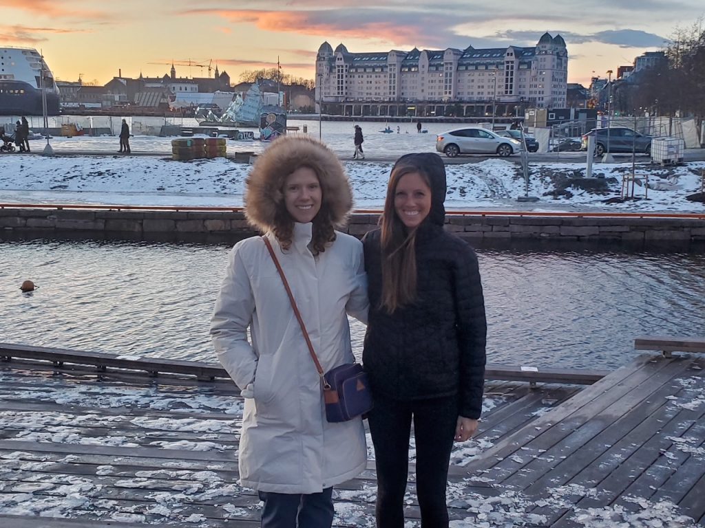 two girl friends all bundled up in front of a snowy Oslo Fjord in the winter