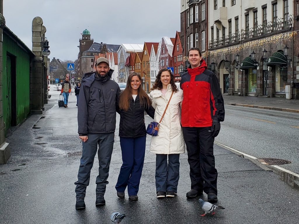 two couples in front of the colorful wooden buildings of Bryggen Wharf, Bergen, Norway