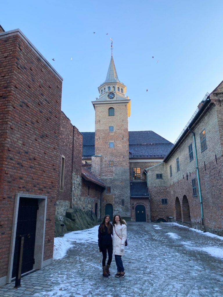Two friends standing outside Akershus Fortress on a snowy winter day in Oslo