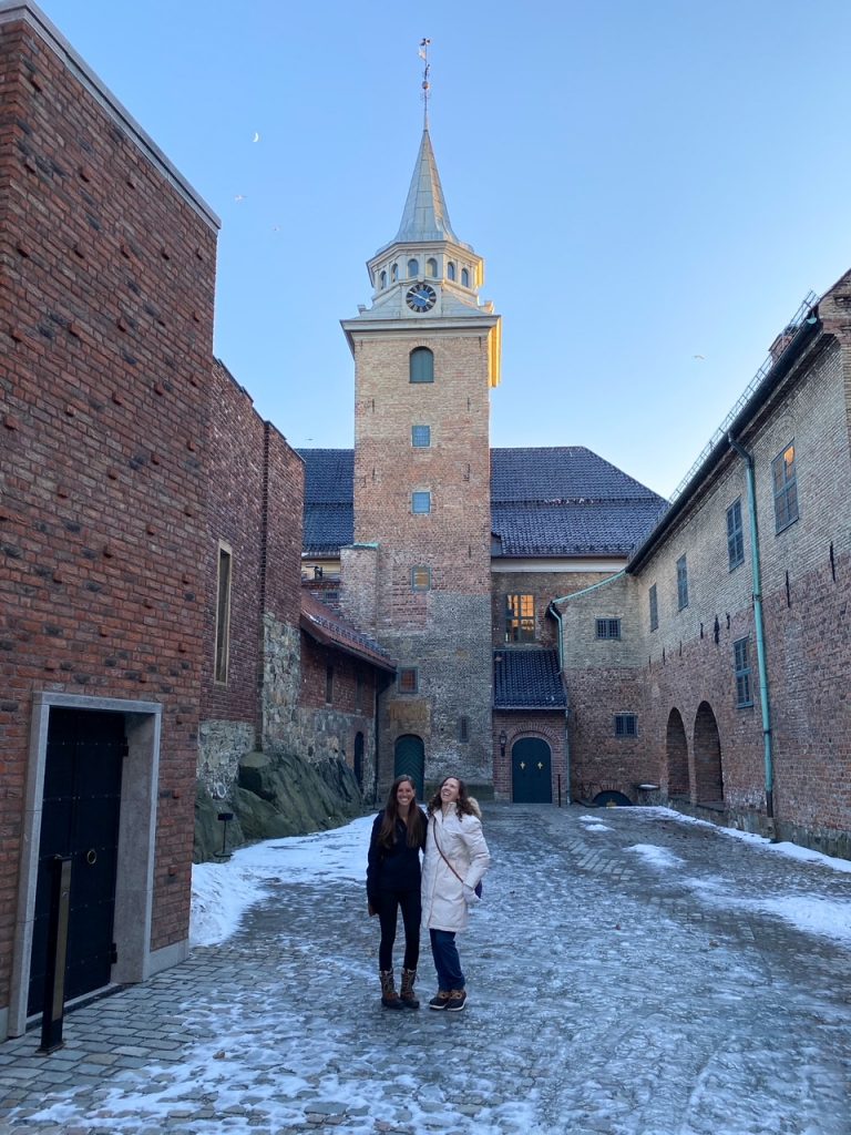 Two best girl friends laughing outside Akershus Fortress on a snowy Sunday afternoon in Oslo in winter