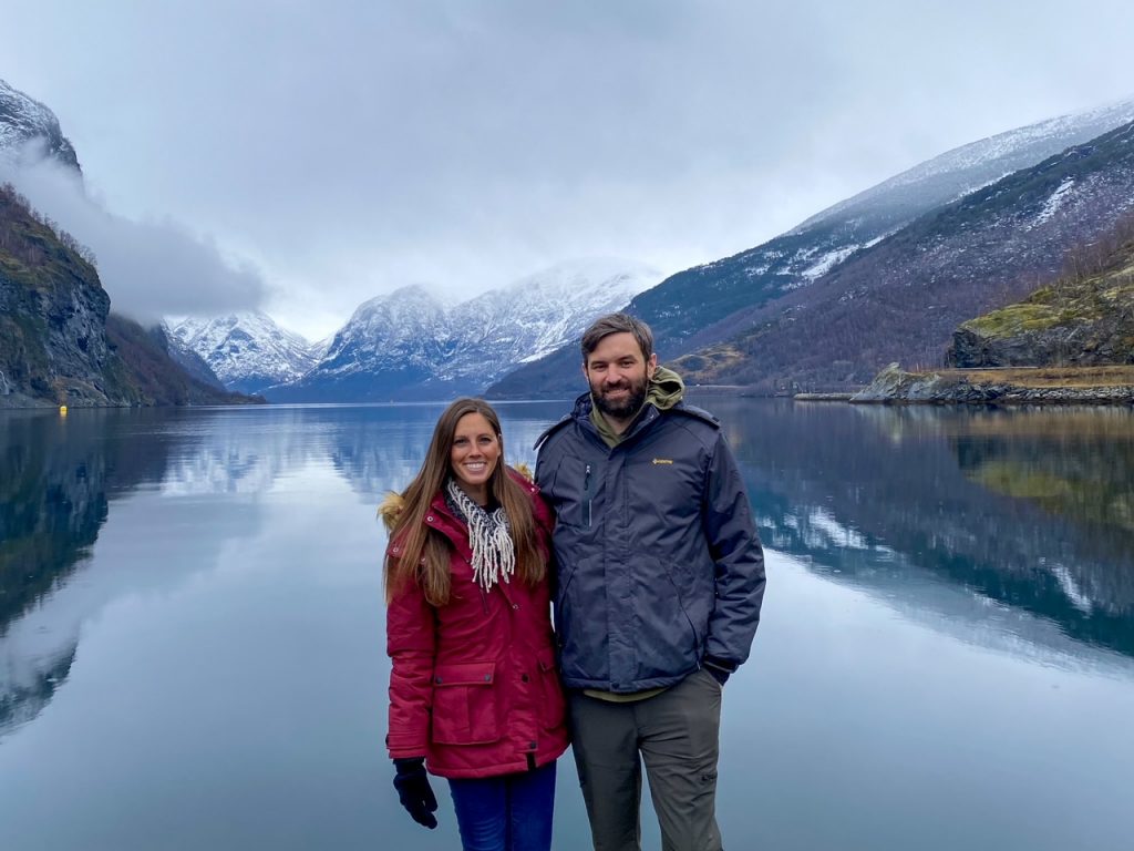 a couple bundled up in their winter gear in front of the Aurlandsfjord at the The Flåm Marina in Norway in winter