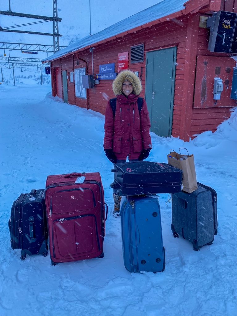 Sara bundled up standing in the snow with all of her group's luggage at the Myrdal train station in Norway in winter