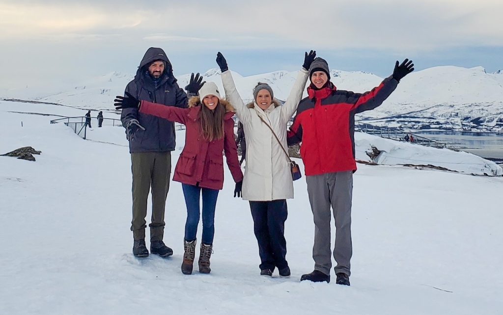 two couples waving at the top of Mount Storsteinen in Tromsø, Norway
