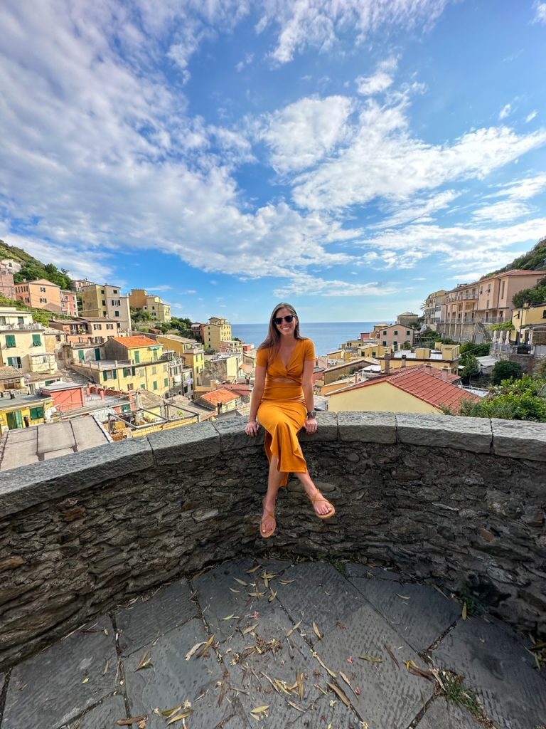 Sara sitting on a ledge in Riomaggiore