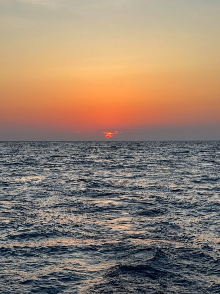 a breathtaking sunset as seen from our Santorini catamaran cruise