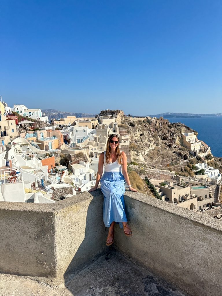 Sara sitting on a ledge in Oia Santorini