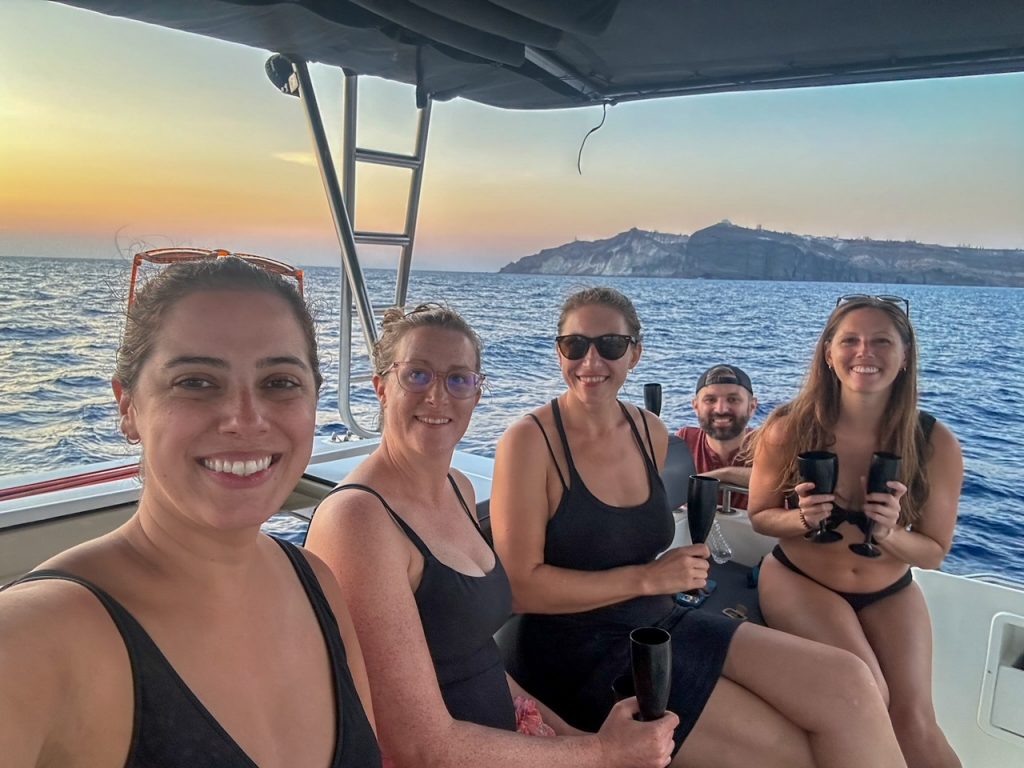 the group having fun sitting next to the captain on the catamaran cruise in Santorini