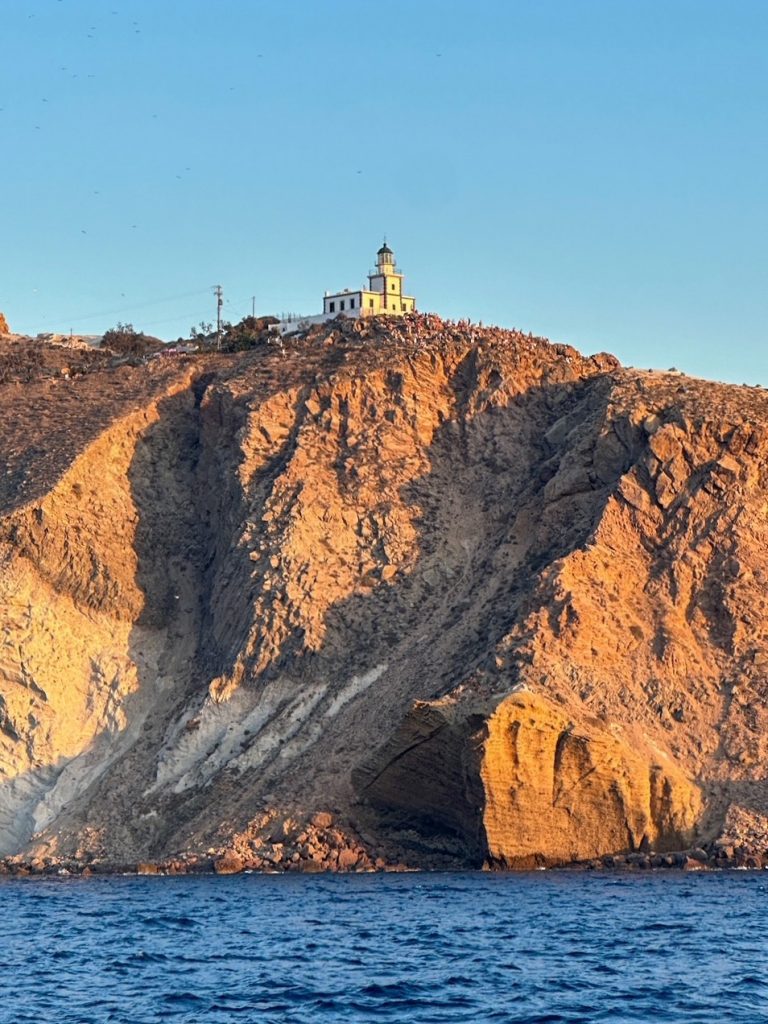 the historic Venetian Akrotiri Lighthouse overlooking the caldera as seen from our Santorini catamaran cruise