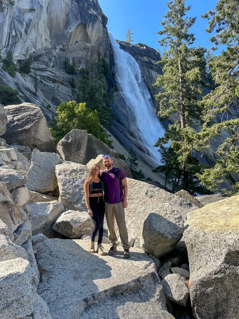 Sara and Tim standing on a rock in front of Nevada Fall in Yosemite National Park