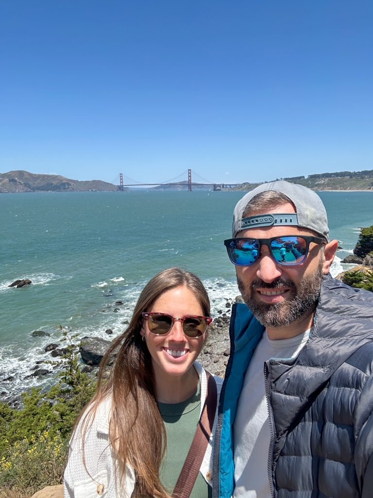 Sara and Tim taking a selfie in front of the Golden Gate Bridge on the Lands End Trail in San Francisco