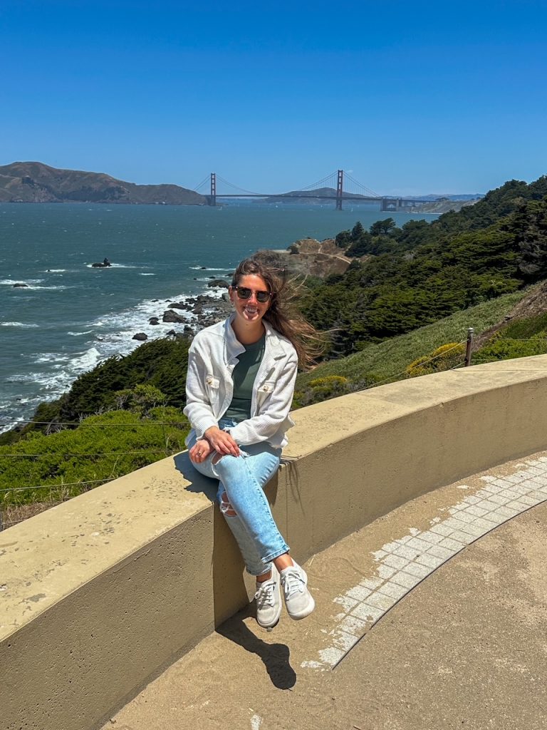 Sara looking wind-swept in front of the Golden Gate Bridge on the Lands End Trail in San Francisco