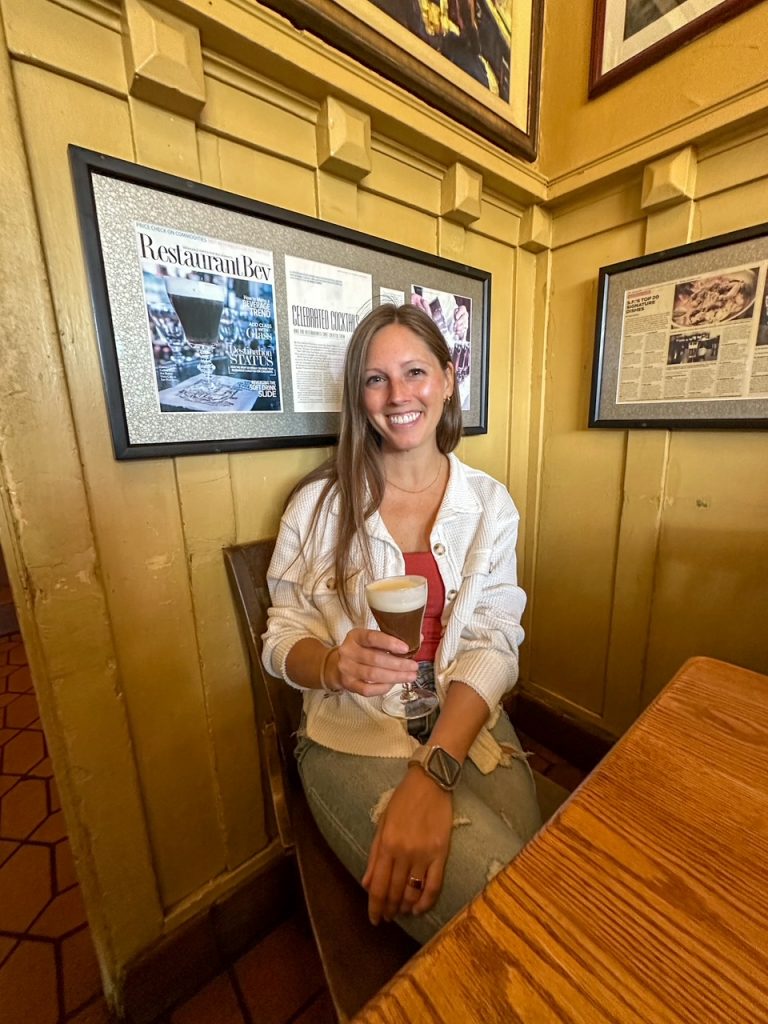Traveler holding an Irish coffee at The Buena Vista Café in San Francisco, a classic road trip stop