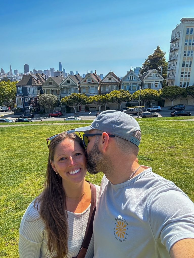 Tim kissing Sara in front of the Painted Ladies at Alamo Square in San Francisco