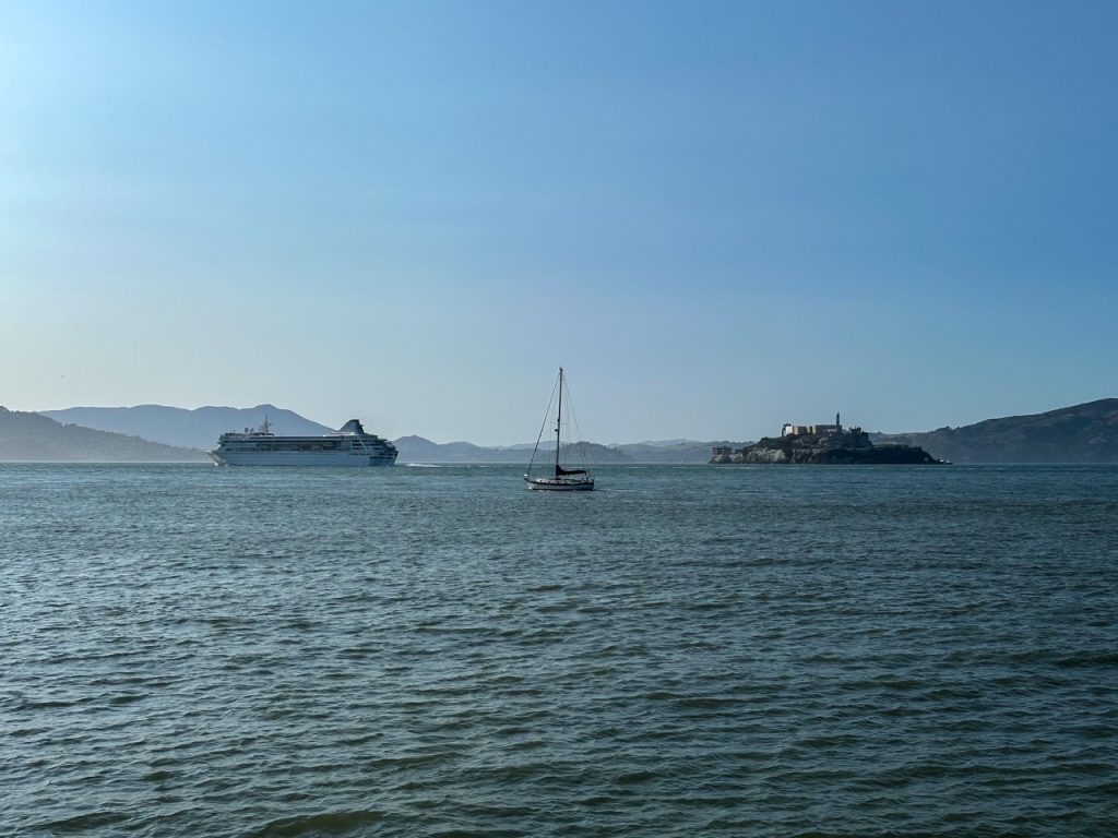 a cruise ship and sailboat passing Alcatraz Island offshore from San Francisco