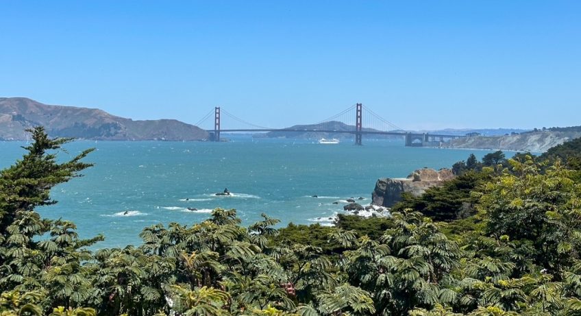 a panoramic view of the Golden Gate Bridge from the Lands End Trail on a clear day in San Francisco