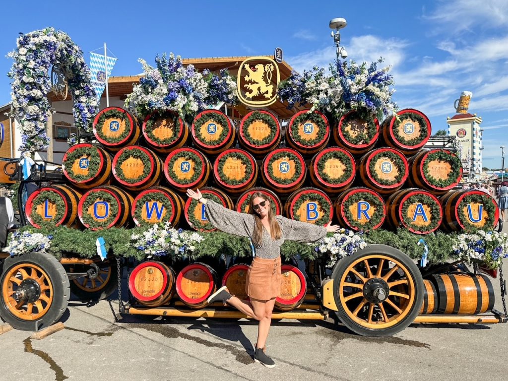 Sara posing in front of a traditional horse-drawn beer keg wagon in Munich
